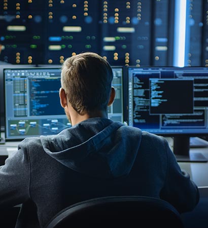 IT Specialist Works on Personal Computer with Screens Showing Software Program with Coding Language Interface. In the Background Technical Room of Data Center with Professional Working